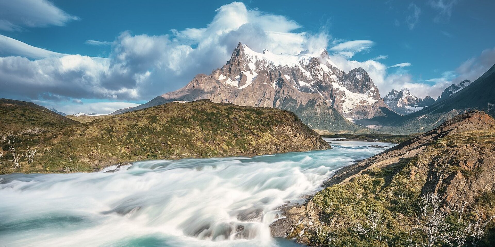 Berg in Patagonien, Chile, mit einem reißenden Fluss im Vordergrund bei dramatischer Wolkenstimmung